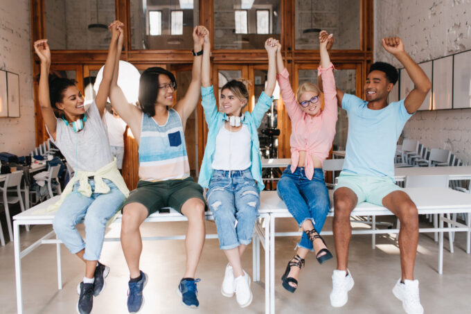 Students congratulate each other with the end of the school year. University friends are happy that they successfully passed the final exams and waving hands..