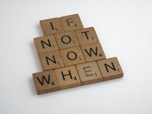 Scrabble tiles spelling out "if not now when" on a white background